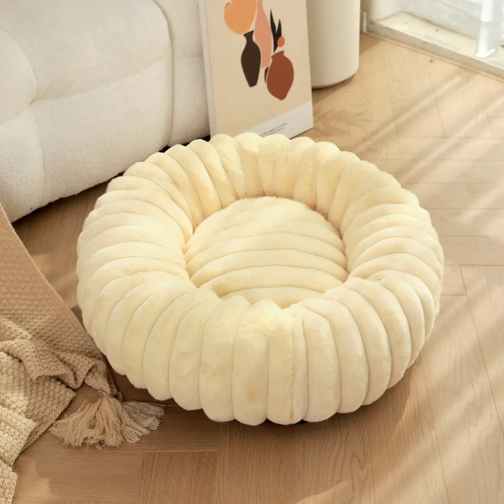Round plush pet bed in beige with raised rim, size L 60cm, on a wooden floor