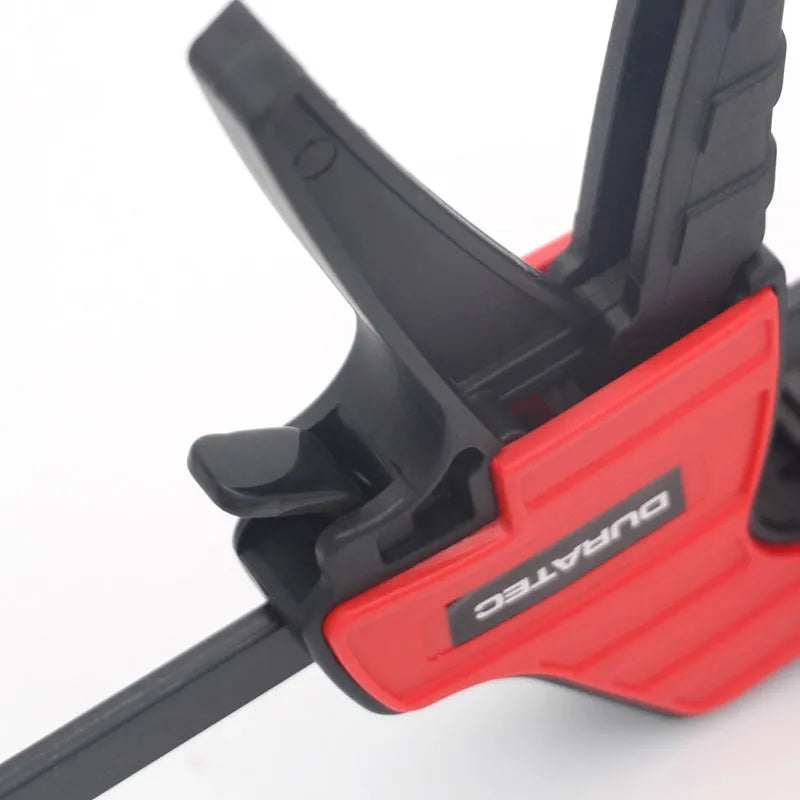 Black plastic woodworking clamp with quick release key and soft rubber grip pads