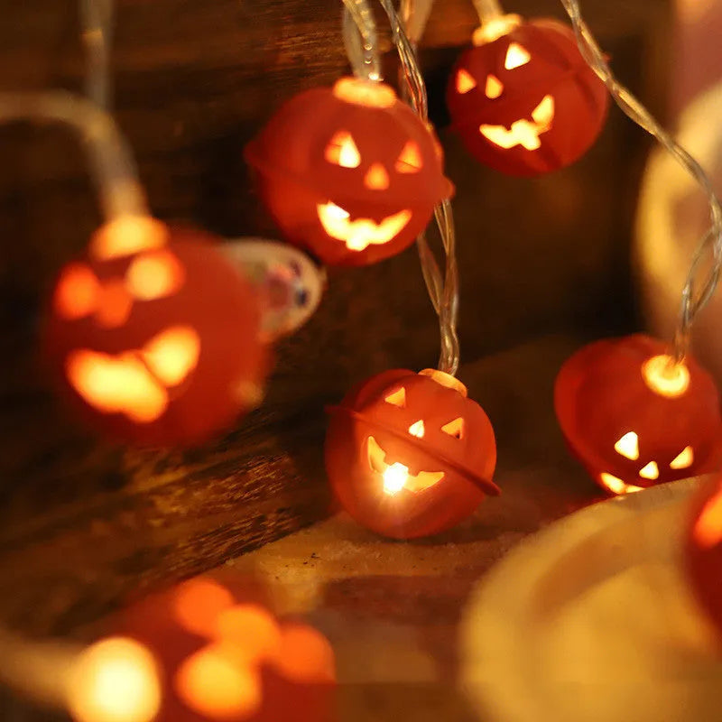 Halloween pumpkin string lights with warm white LEDs and iron pendants on a dark background