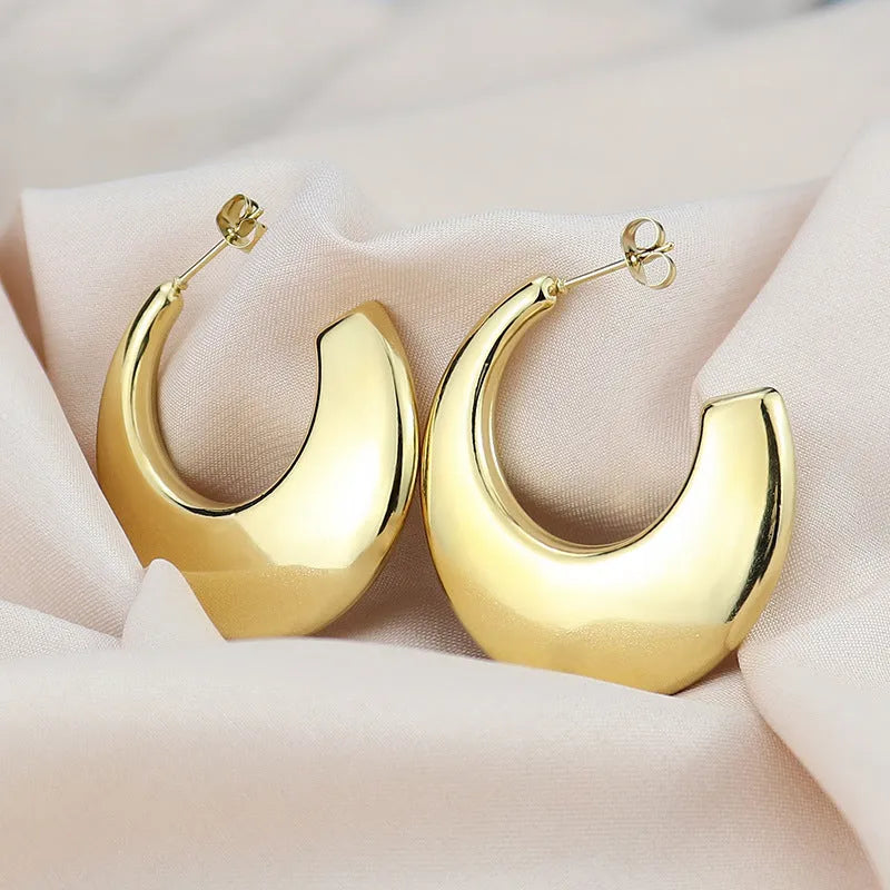 Two pairs of geometric thread stud earrings in gold and steel colour on a flat surface