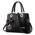 Structured black retro handbag with gold zip and adjustable shoulder strap on a table.