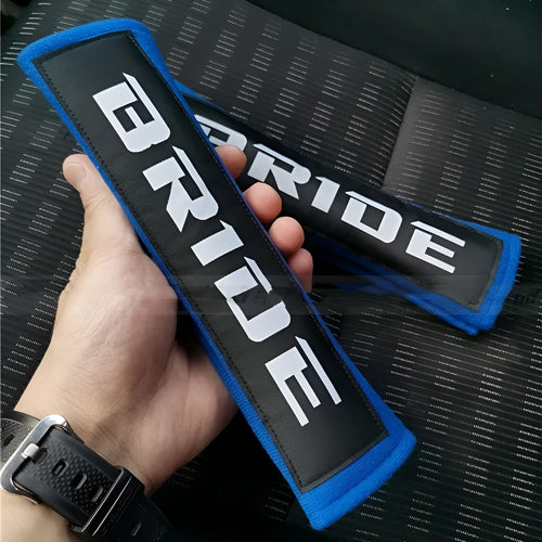 Pair of black car seatbelt shoulder pads showing embroidery detail and thickness