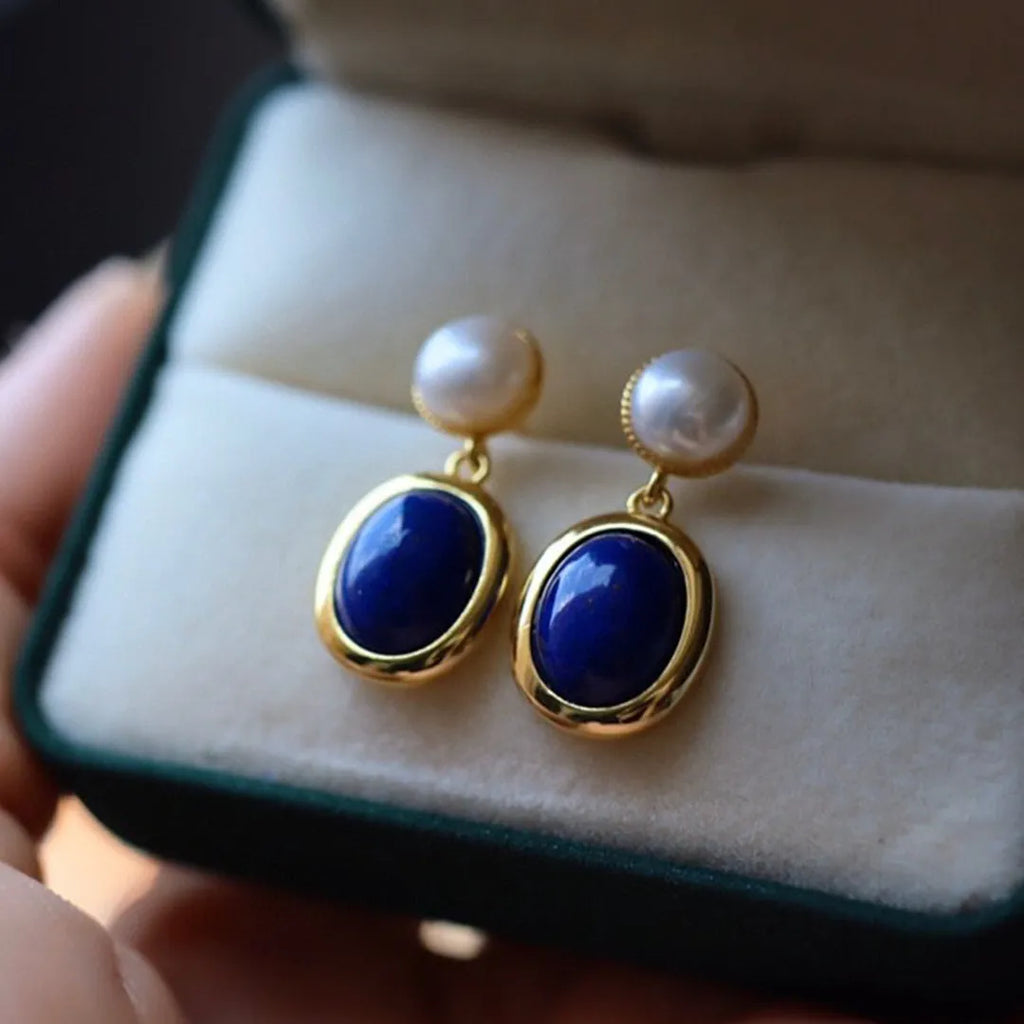 A pair of simple 925 silver earrings featuring a blue lapis lazuli pearl and auspicious pattern detailing.