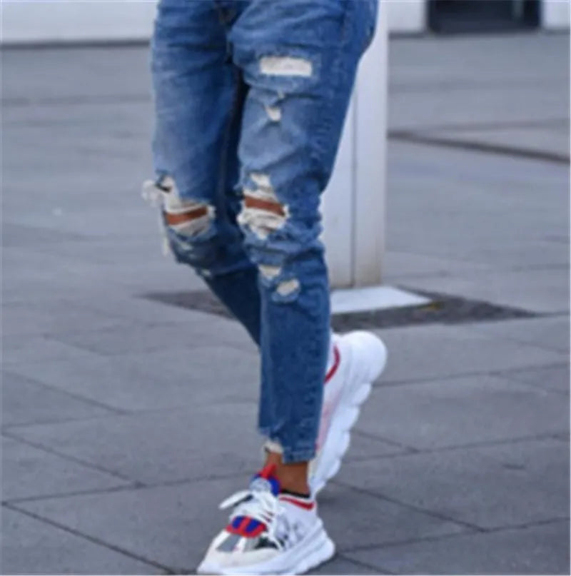Men's deep blue cotton jeans with distressed hole detailing laid flat.