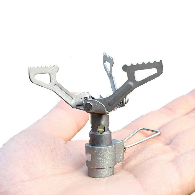 Compact portable camping stove with one-piece steel body and folded legs, shown with a propane canister.