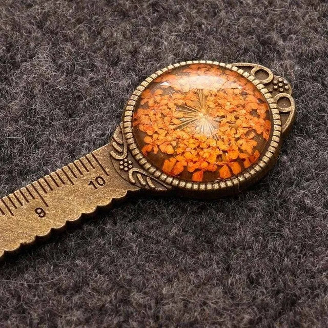 Handmade dried gypsophila and clover flower bookmark ruler on a book, showing 12cm length.