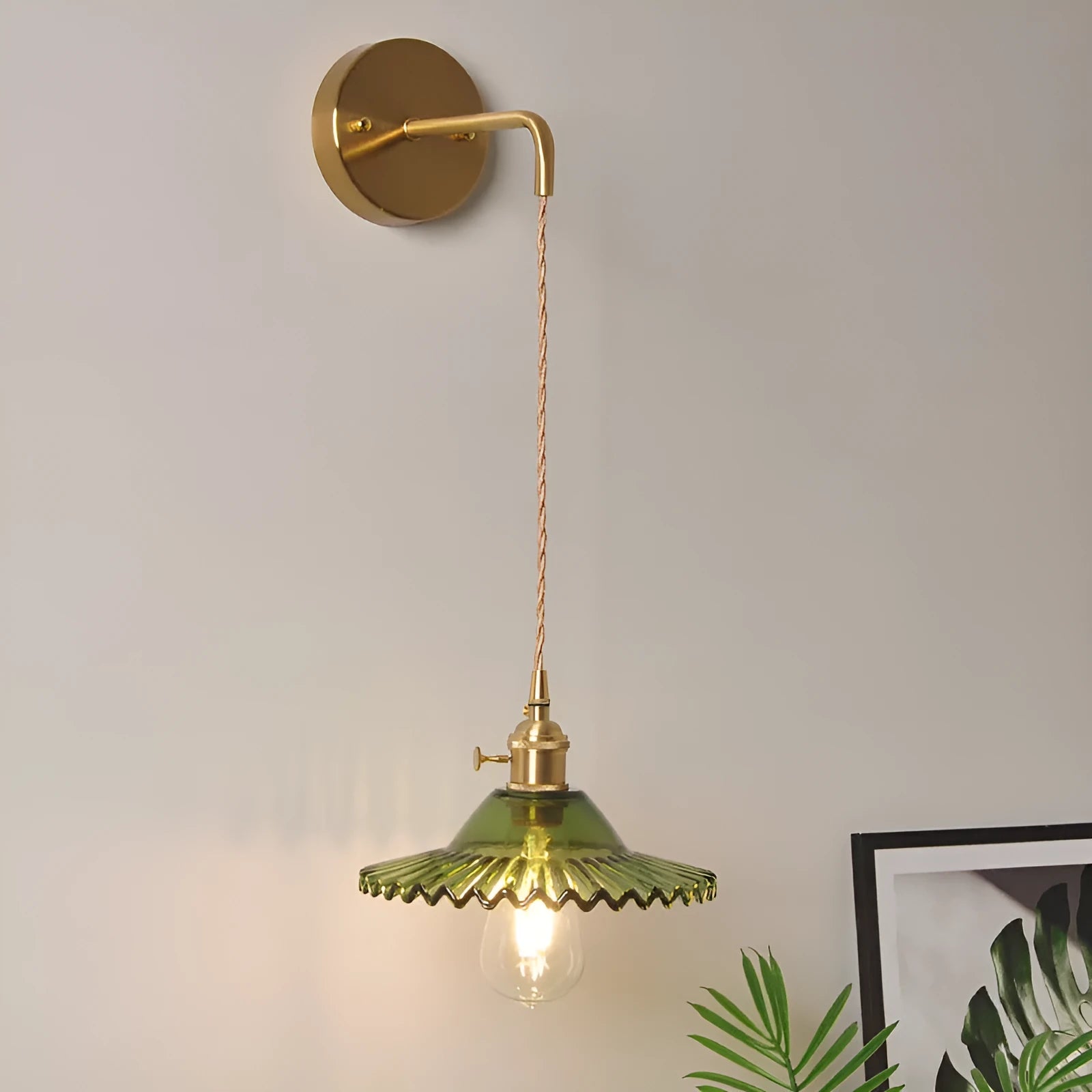 Retro brass lotus wall lamp with a smoky grey glass shade hanging on a 30cm wire beside a bed.