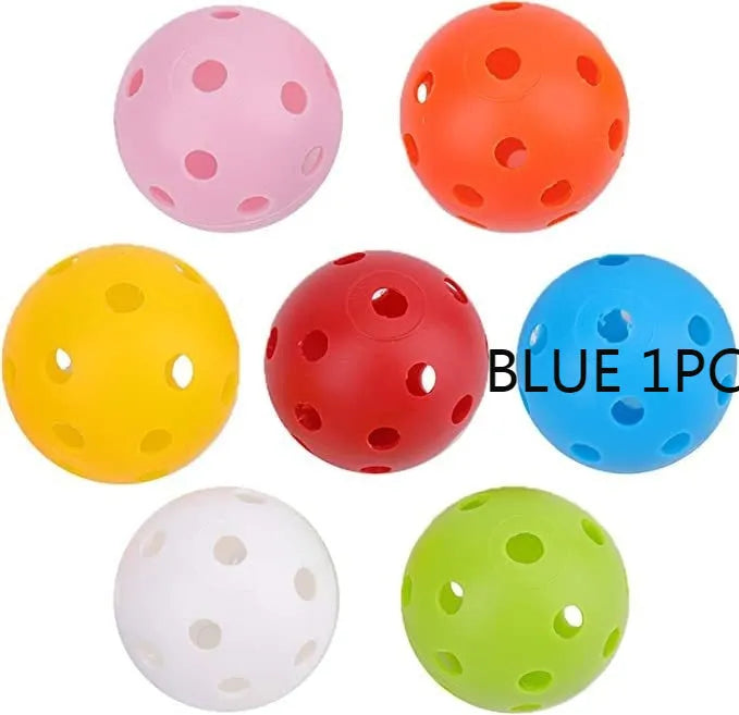 Multi-colour golf practice balls with 26-hole design on a green surface next to a net pocket.