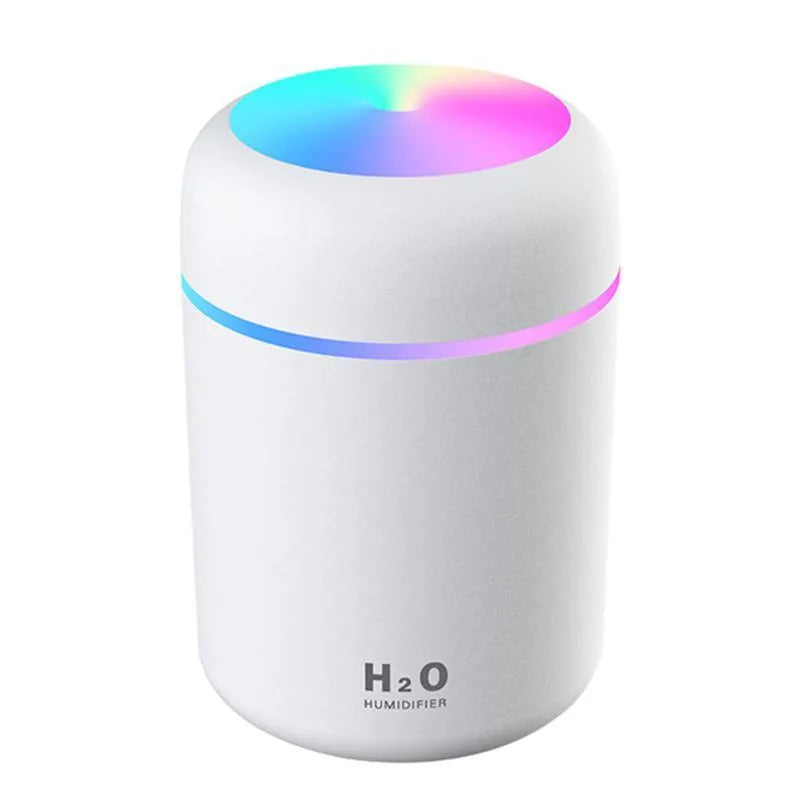 Pink USB mini humidifier with LED lights on wooden desk beside laptop