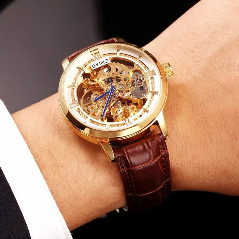 Men's automatic mechanical watch with skeleton dial, leather strap, and gold-tone case on a neutral background
