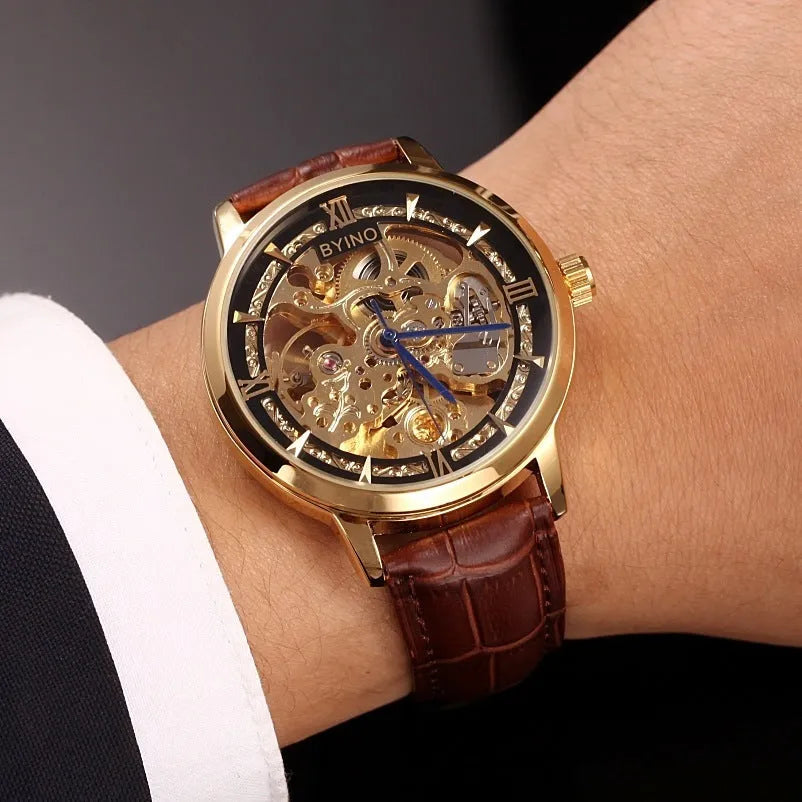 Men's automatic mechanical watch with skeleton dial, leather strap, and gold-tone case on a neutral background