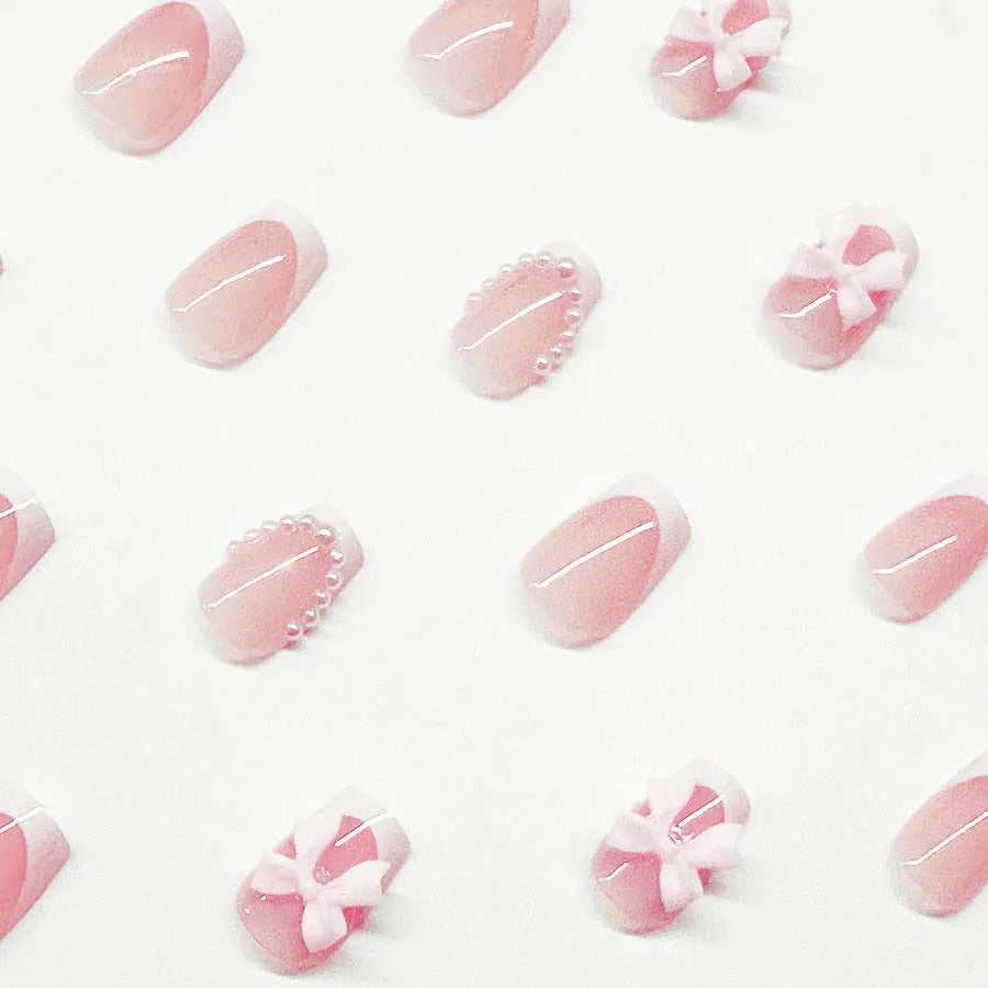 Set of short square press-on nails with white French tips, bow patterns, and tulip designs next to S274 glue bottles.