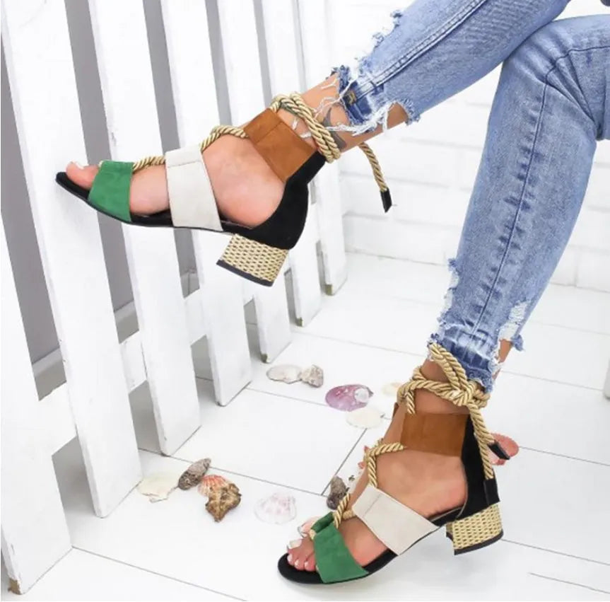 Women's beige suede sandals with thick heel and ankle strap on a foot.