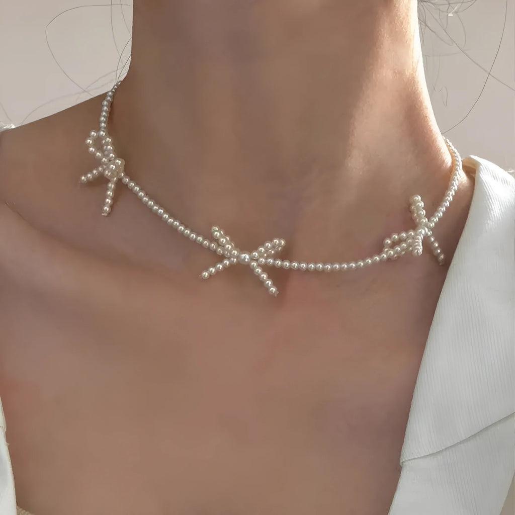 White bow pearl necklace with geometric clasp on woman at clavicle length