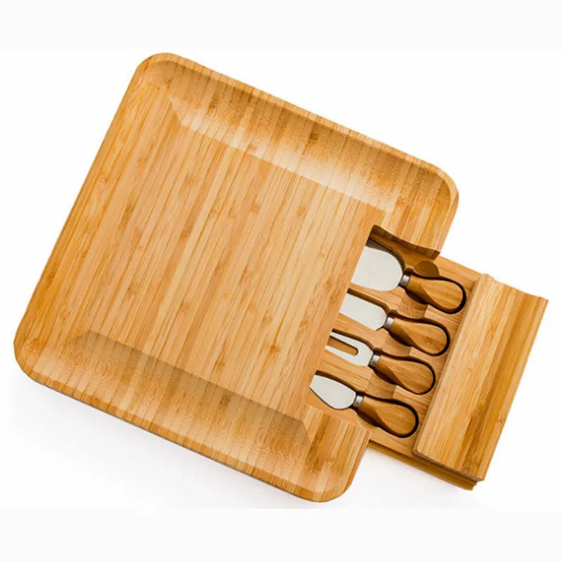 Square bamboo cutting board with drawer holding four-piece knife and fork set in wood colour