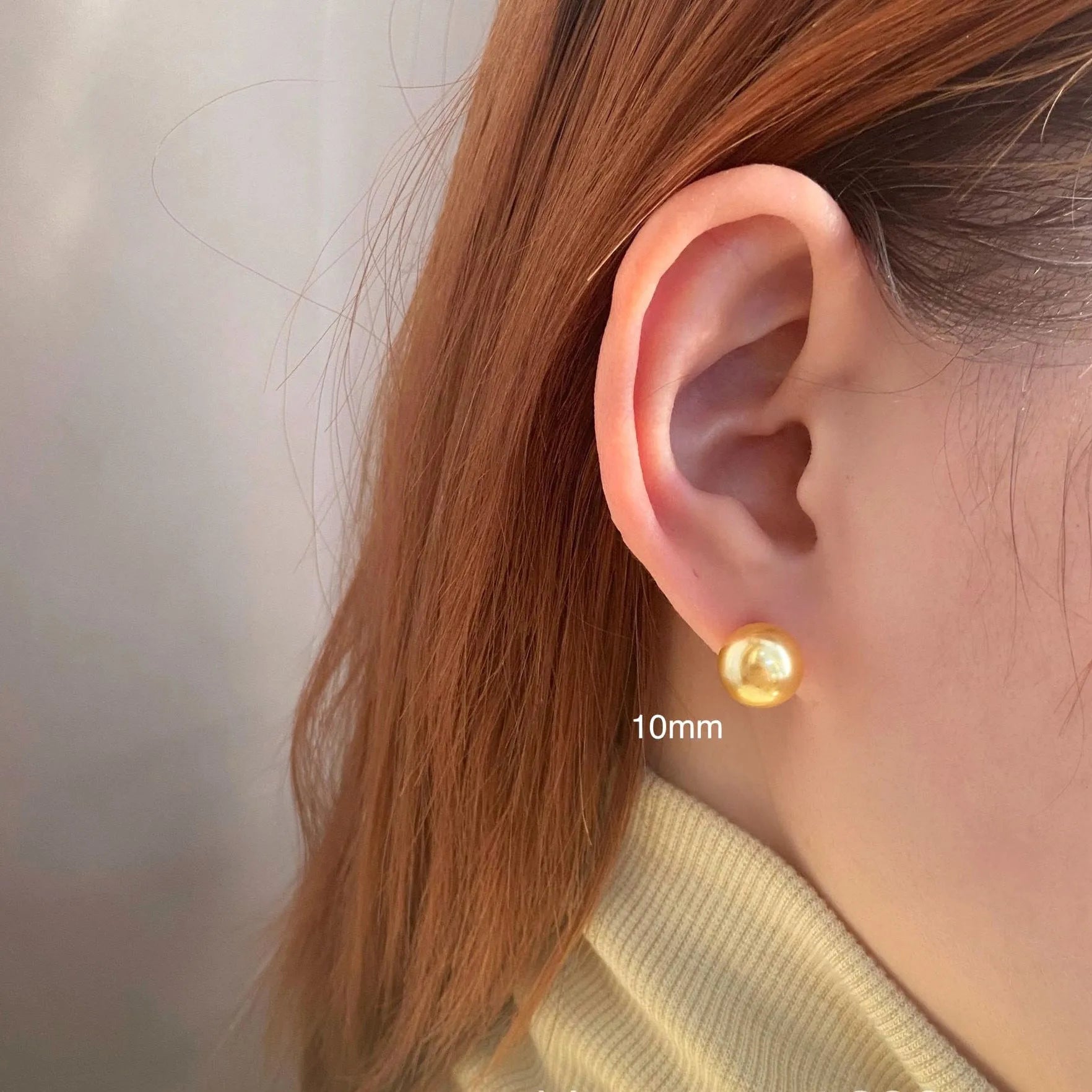 A pair of large pearl stud earrings with a geometric silver setting on a white background.