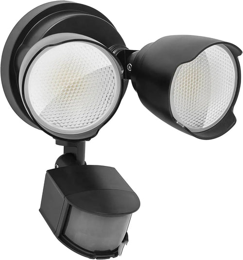 White outdoor LED security flood light with motion sensor mounted on a wall beside a garage door.