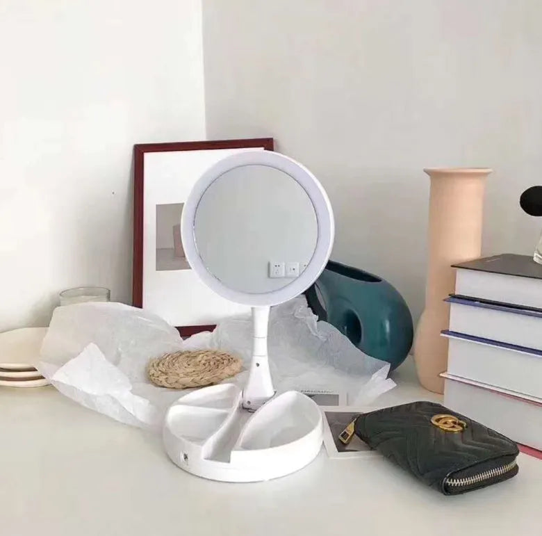 White acrylic LED vanity mirror with foldable base and storage compartment, shown unfolded on a table.