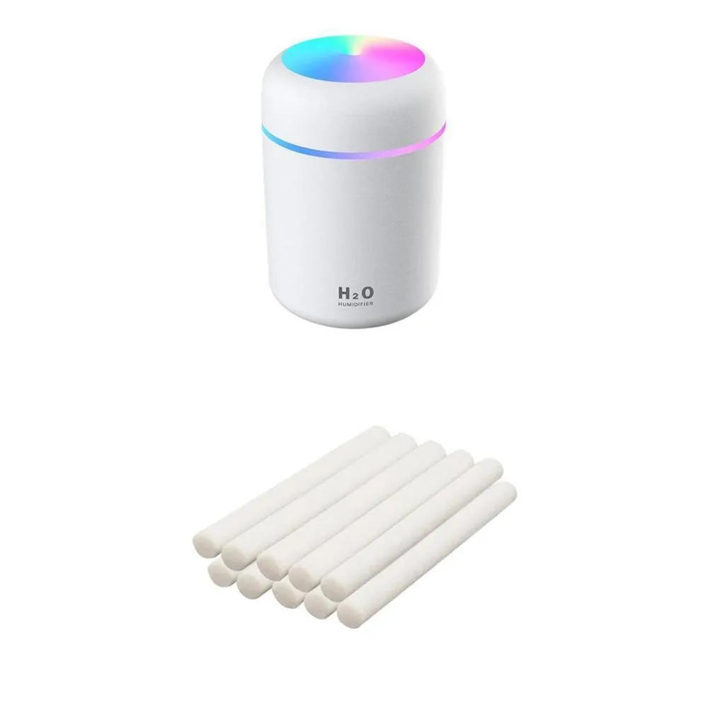 Pink USB mini humidifier with LED lights on wooden desk beside laptop