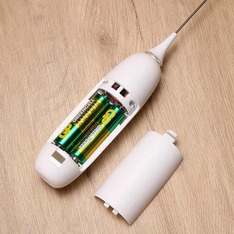 A handheld electric milk frother in black and white colours on a kitchen counter.