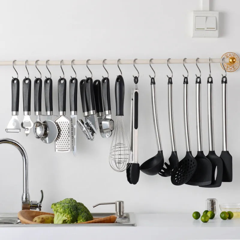 Black silicone kitchen utensil set with stainless steel handles showing four different utensil types