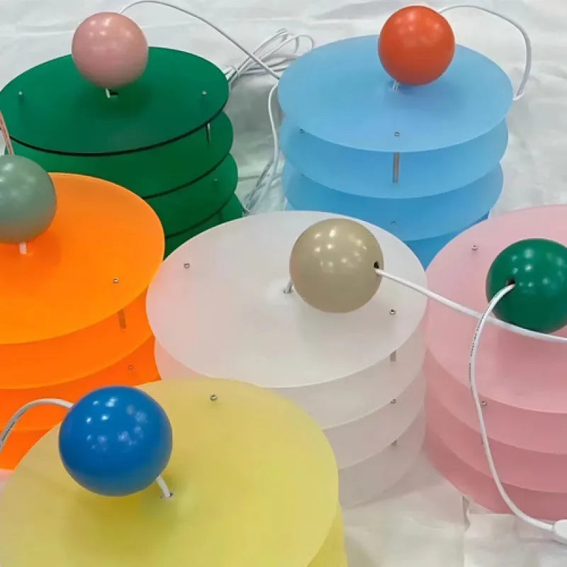 Macaron-shaped adjustable chandelier light fixture with a frosted shade, shown in a dining setting.