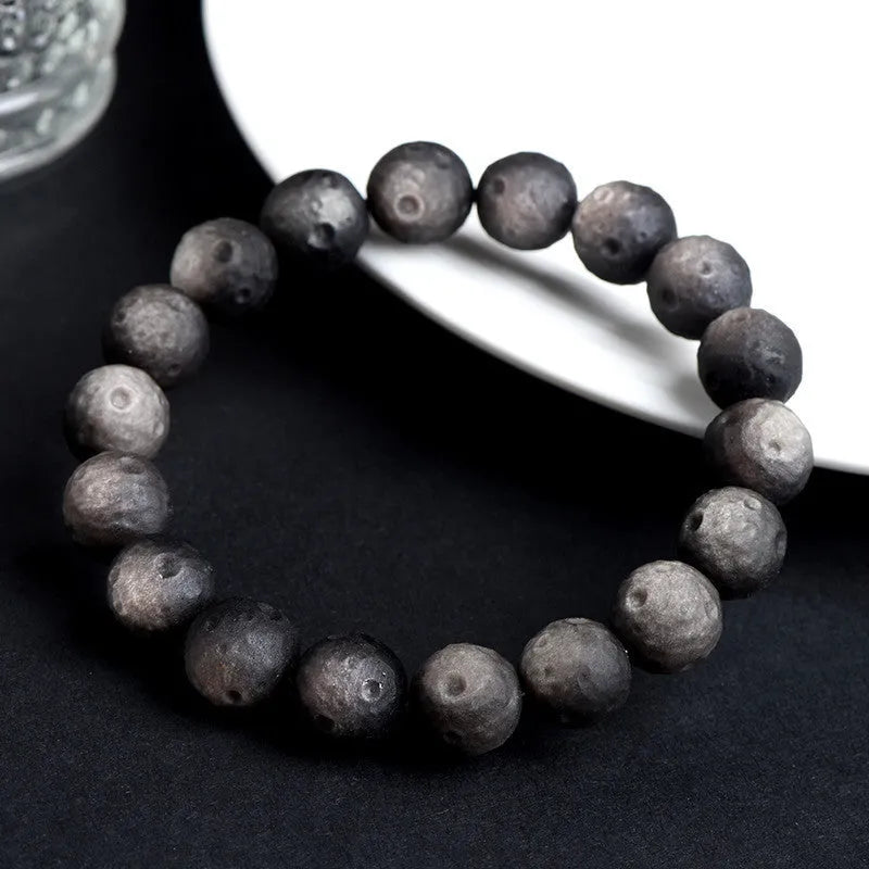 Unisex natural obsidian crater ball bracelet in silver stone meteorite colour with textured beads.