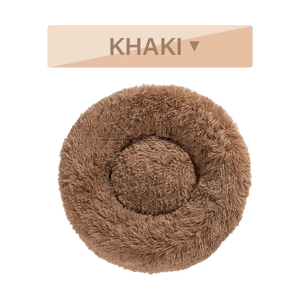 A fluffy, round donut-shaped dog bed with a raised rim in long plush fabric.