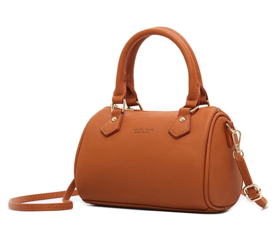 Ladies pillow crossbody bag in PU with zip closure and letter detail, shown in available colours.