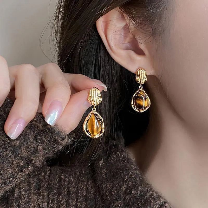Three pairs of geometric tassel earrings in Maillard, amber, and tigereye colours on a white background
