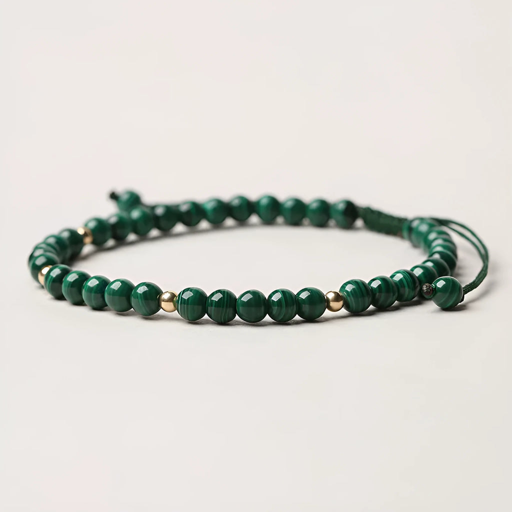 Women's malachite and gold bead bracelet with animal zodiac charm on woven strap.