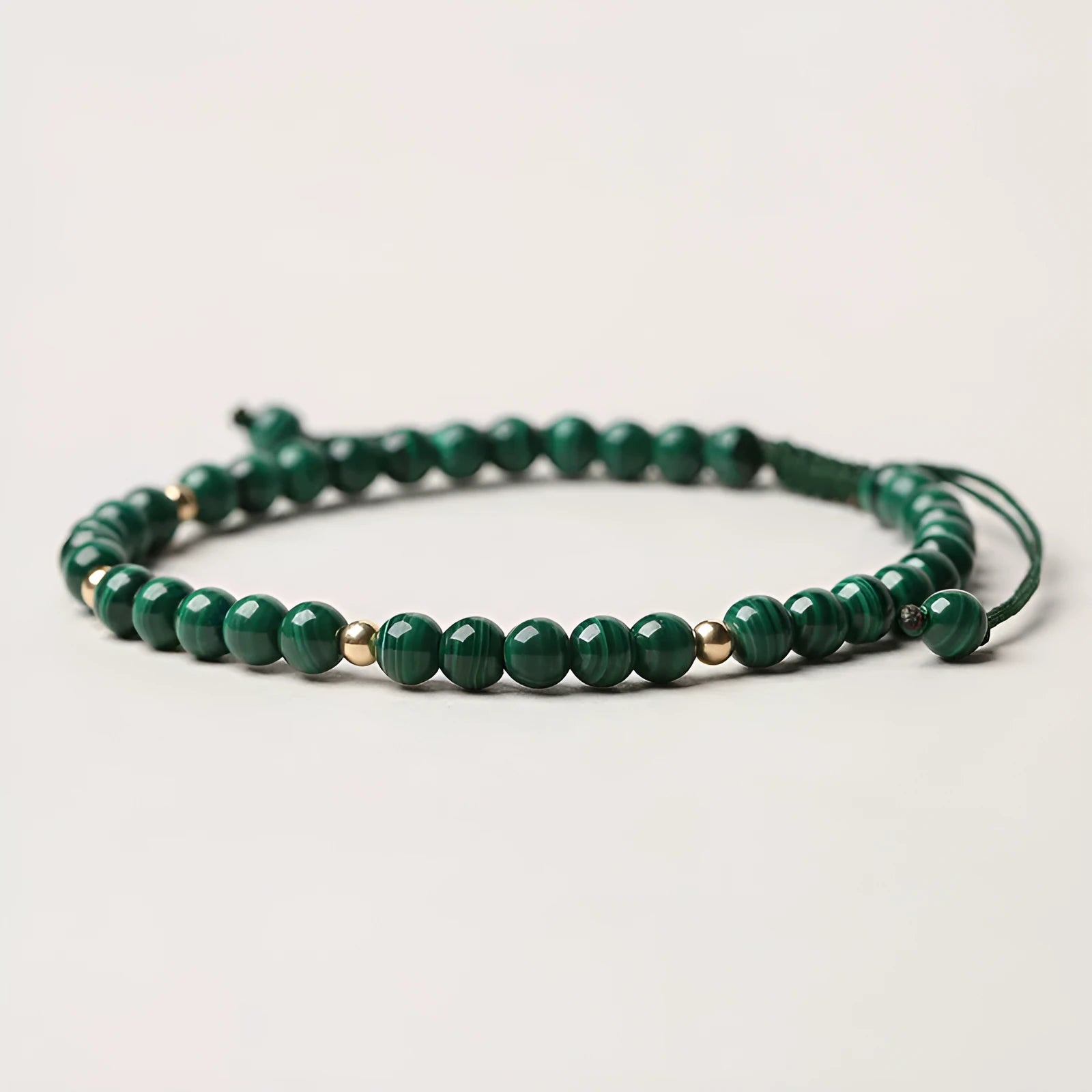 Women's malachite and gold bead bracelet with animal zodiac charm on woven strap.