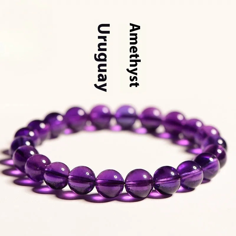 Natural Uruguayan amethyst bead bracelet with scattered polished crystals in deep violet hues on a white background.