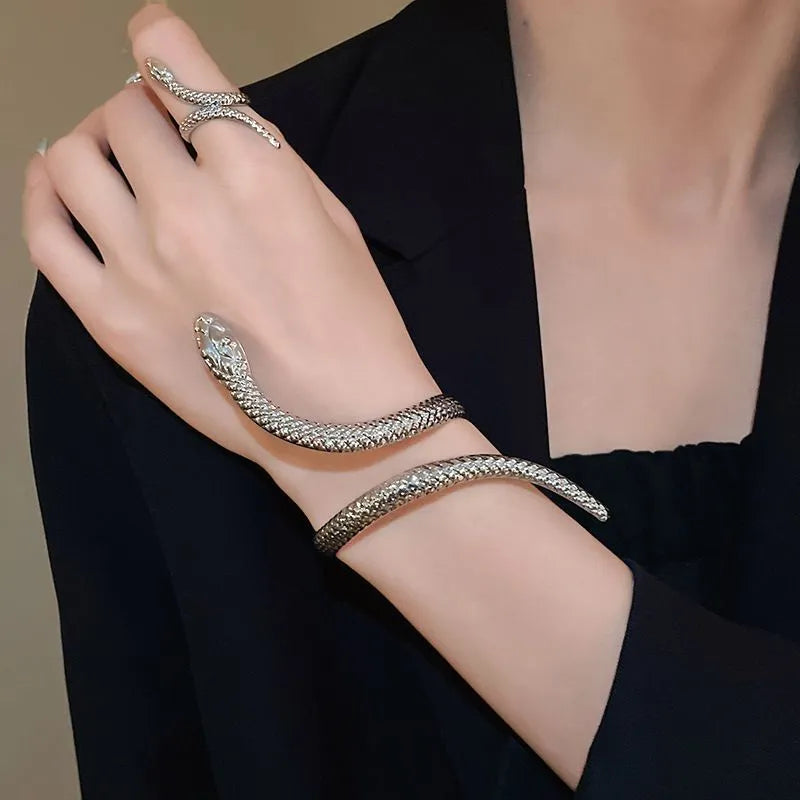 Gold tone snake-inspired bracelet and ring set with exaggerated twisted winding design on white background