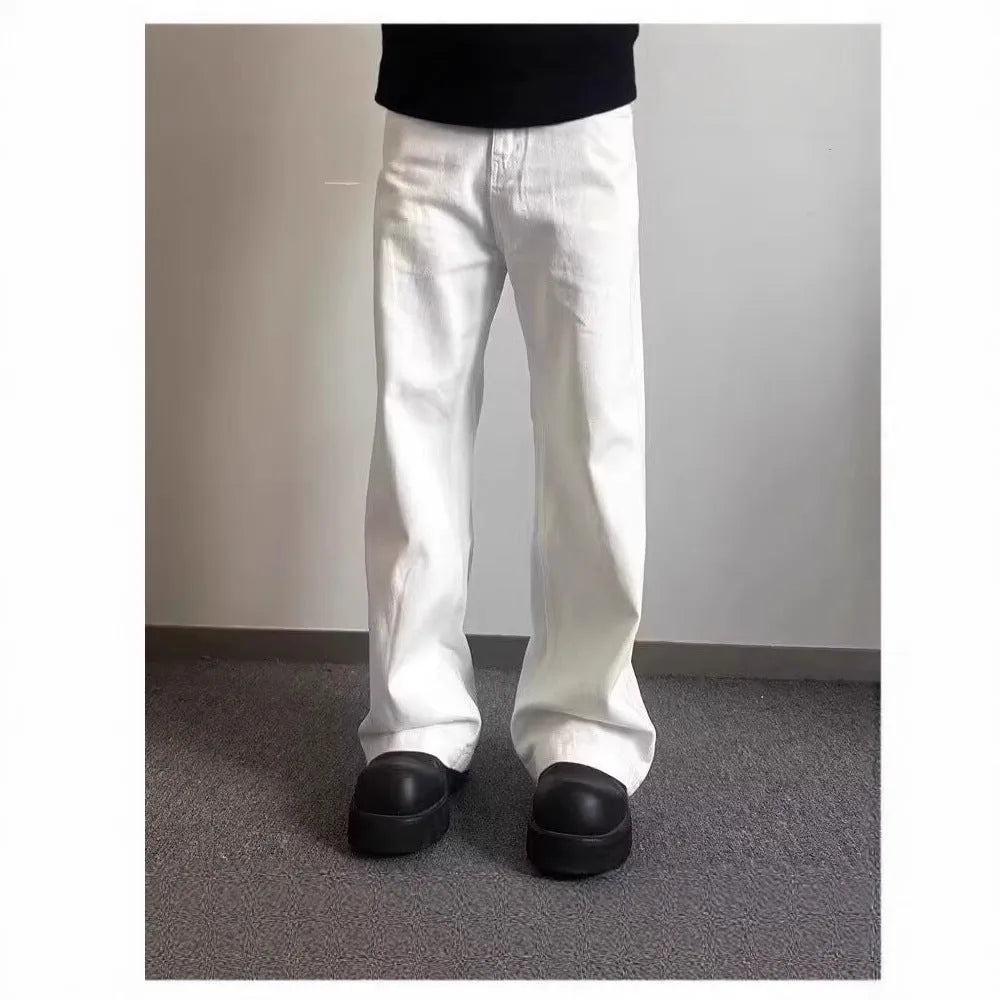 A man wearing white loose straight-leg cotton jeans with a mid-waist and zipper fly.