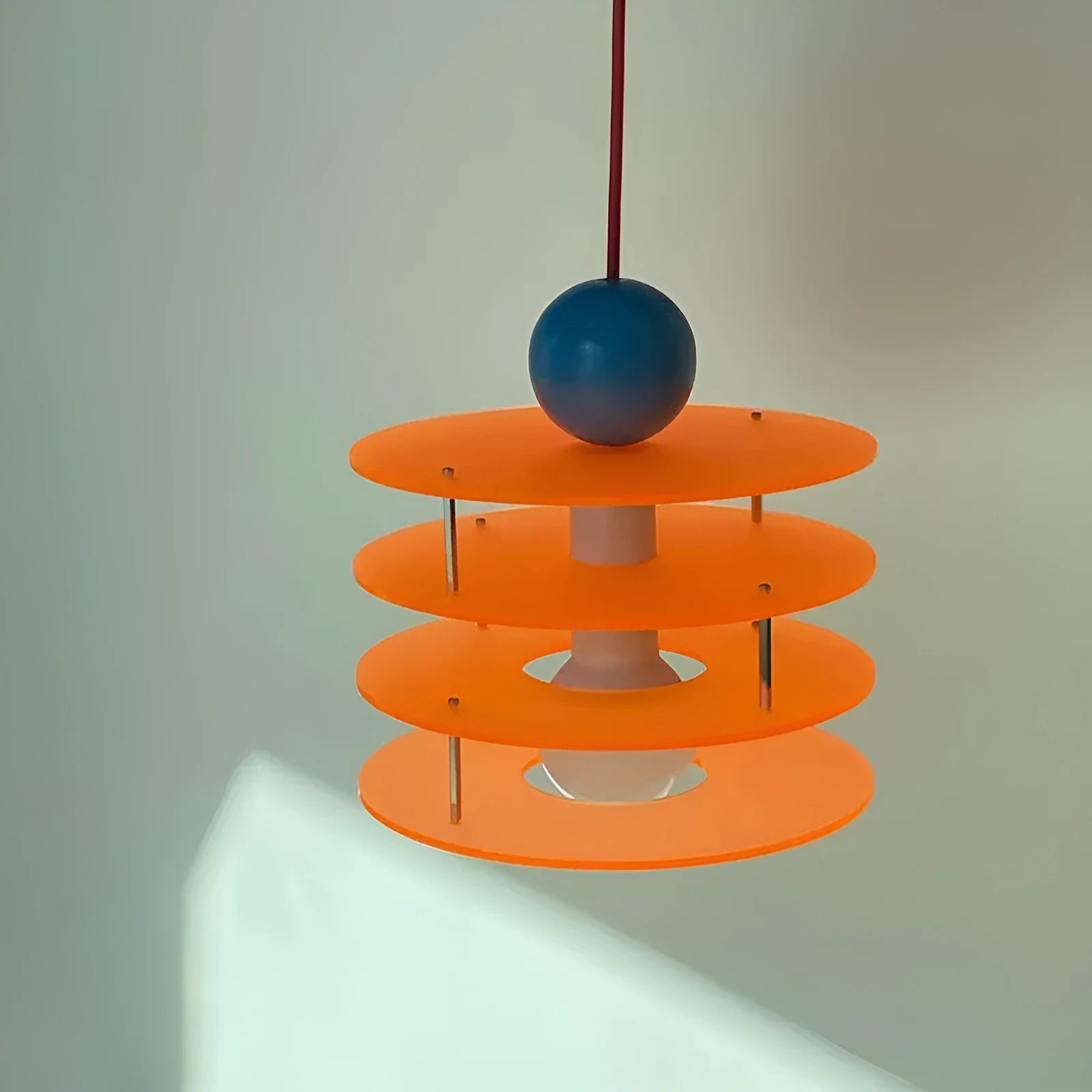 Macaron-shaped adjustable chandelier light fixture with a frosted shade, shown in a dining setting.