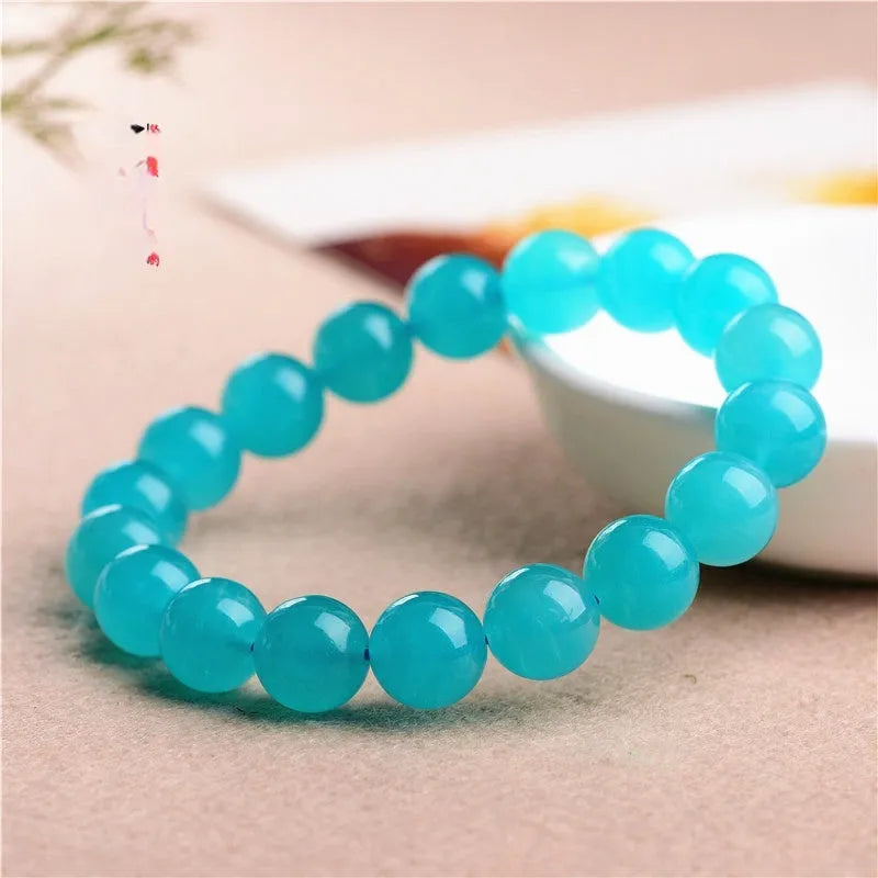 Loose natural Amazonite beads in ice blue colour, showing polished surfaces and irregular scattered shapes next to a finished bracelet.