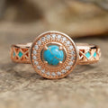 Women's turquoise ethnic geometric ring with micro inlaid zircon in rose gold coloured copper on a white background.