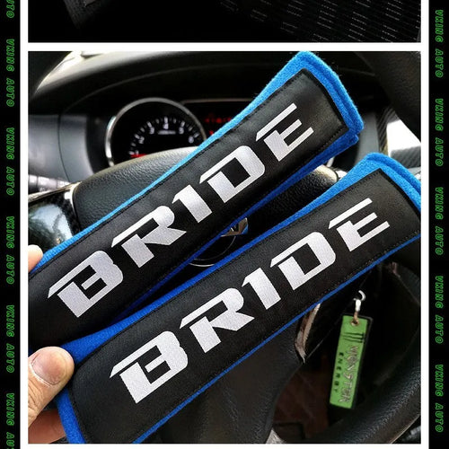 Pair of black car seatbelt shoulder pads showing embroidery detail and thickness