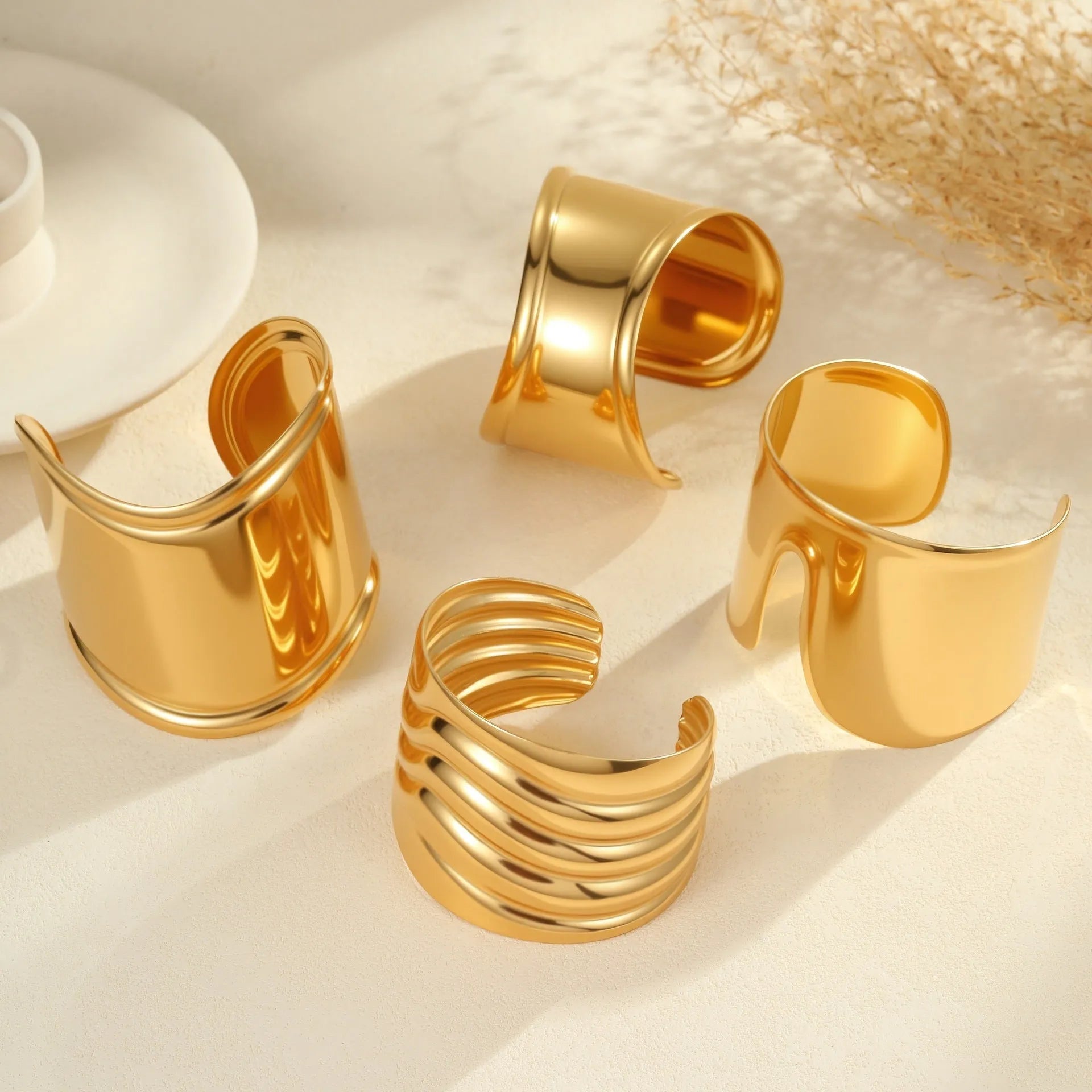 Women's wide stainless steel bracelet with 18K gold plating in a wave and geometric design.