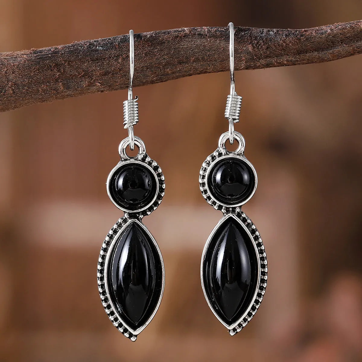 A pair of vintage-style geometric drop earrings with black and purple electroplated pendants on a white background.