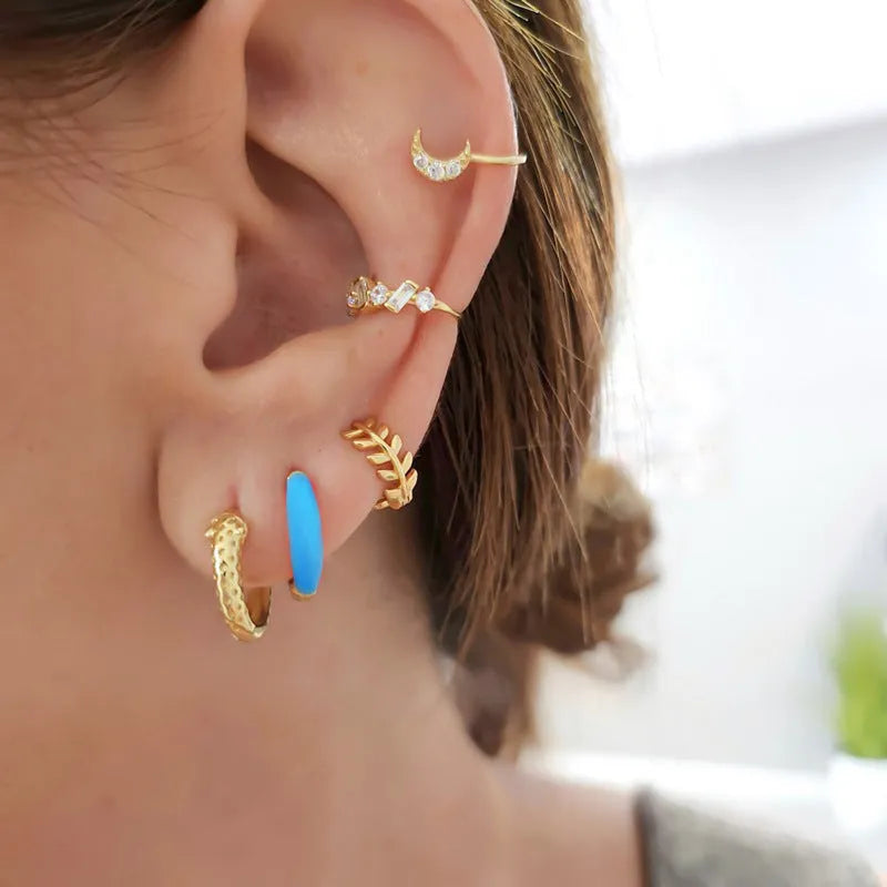 A pair of glossy light green epoxy oval earrings with a U-shaped curve and silver-coloured post on a grey background.
