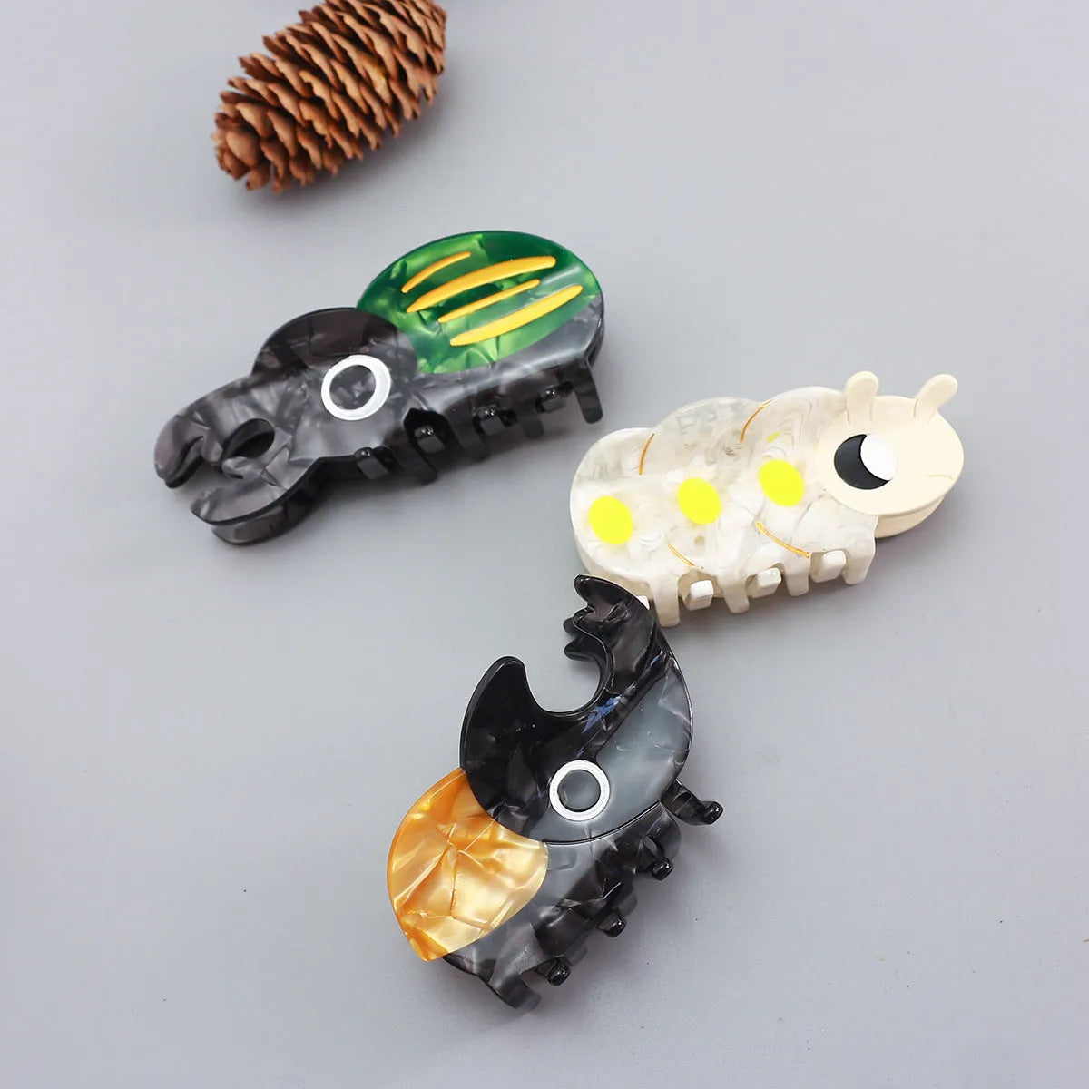 Handmade cellulose acetate beetle hair grip with cartoon caterpillar design in green, orange, or white colour options