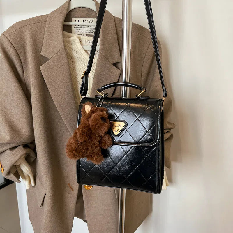 Mini PU backpack in brown with polyester lining, phone pocket, stitching detail, and optional pendant