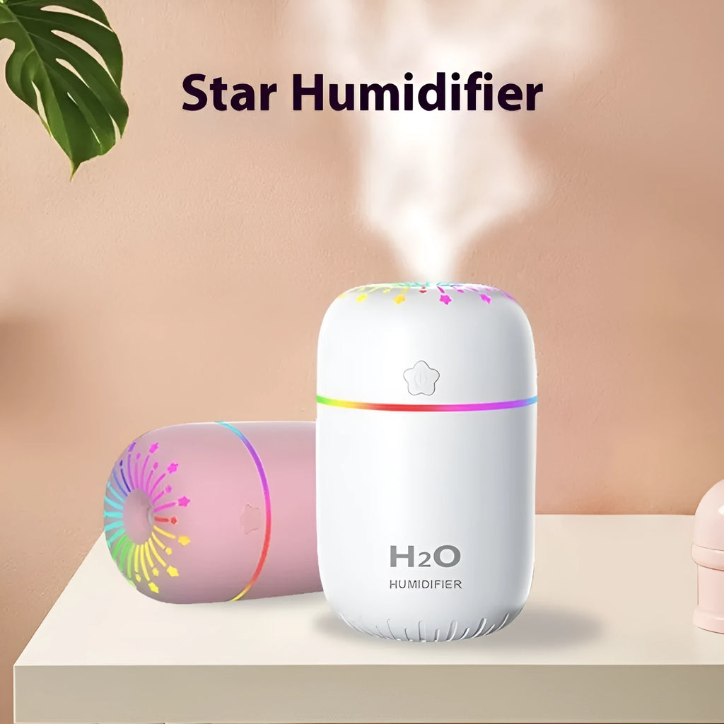 Small white USB humidifier with water tank on a wooden desk next to a laptop.
