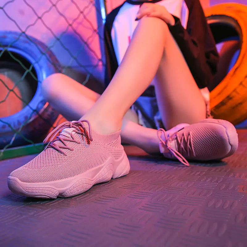 Women's low-top white sport shoes with thick rubber sole and woven upper, showing front strap closure.