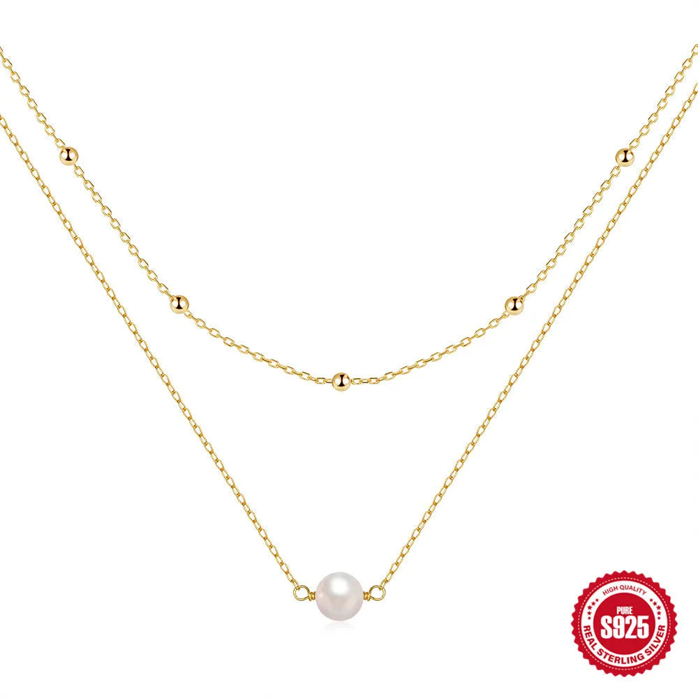 Women's double layer sterling silver necklace with geometric pendant and twin pearls, shown in gold and white gold plating.