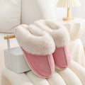 Brown plush indoor slippers for women with a non-slip PVC sole on a wooden floor.