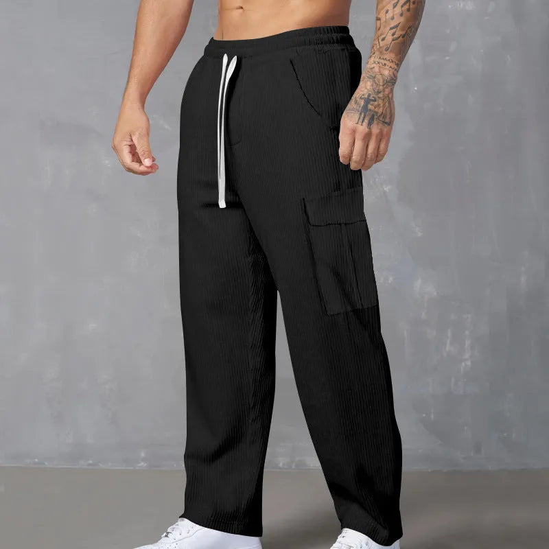 Men's straight-leg corduroy trousers in navy blue, showing loose fit and drawstring waist detail.