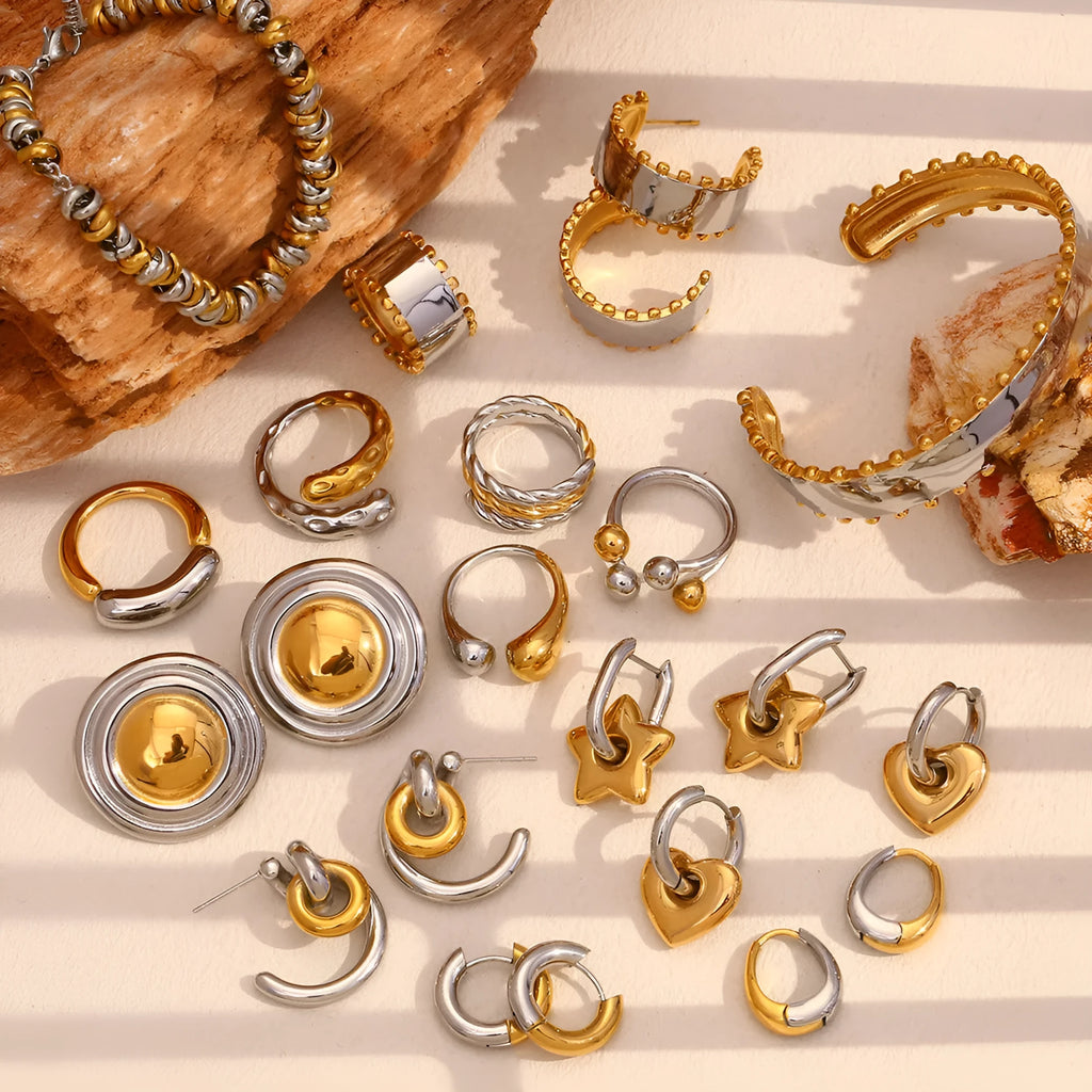 Geometric gold-toned jewellery set on a grey background, showing necklace, bracelet, and round earrings made from stainless steel.